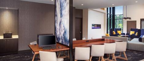 Habitación de hotel moderna con un escritorio de madera, un televisor de pantalla plana y un cuadro abstracto de gran tamaño. Cuenta con un sofá y una mesa de centro en la zona de estar.