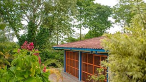 Ein Gebäude mit blau-orangem Anstrich, umgeben von üppigem Grün und Bäumen.