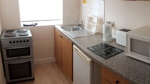 A compact kitchen with a stove, oven, microwave, and a sink. - Royal Windsor Holiday Apartments (Blackpool)