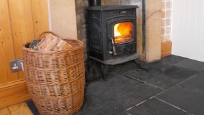 A wood-burning stove with a basket of firewood beside it. - Historic, homely village retreat with log fires, in stunning Borders. Sleeps 4/6 (Allanton)