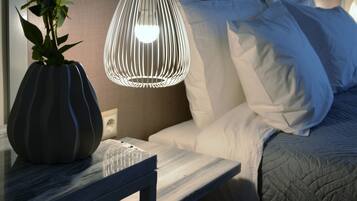 A modern hotel room with a bed, bedside table, and a decorative vase with flowers.