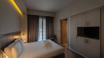 A modern hotel room with a large bed, a TV, and a wardrobe.
