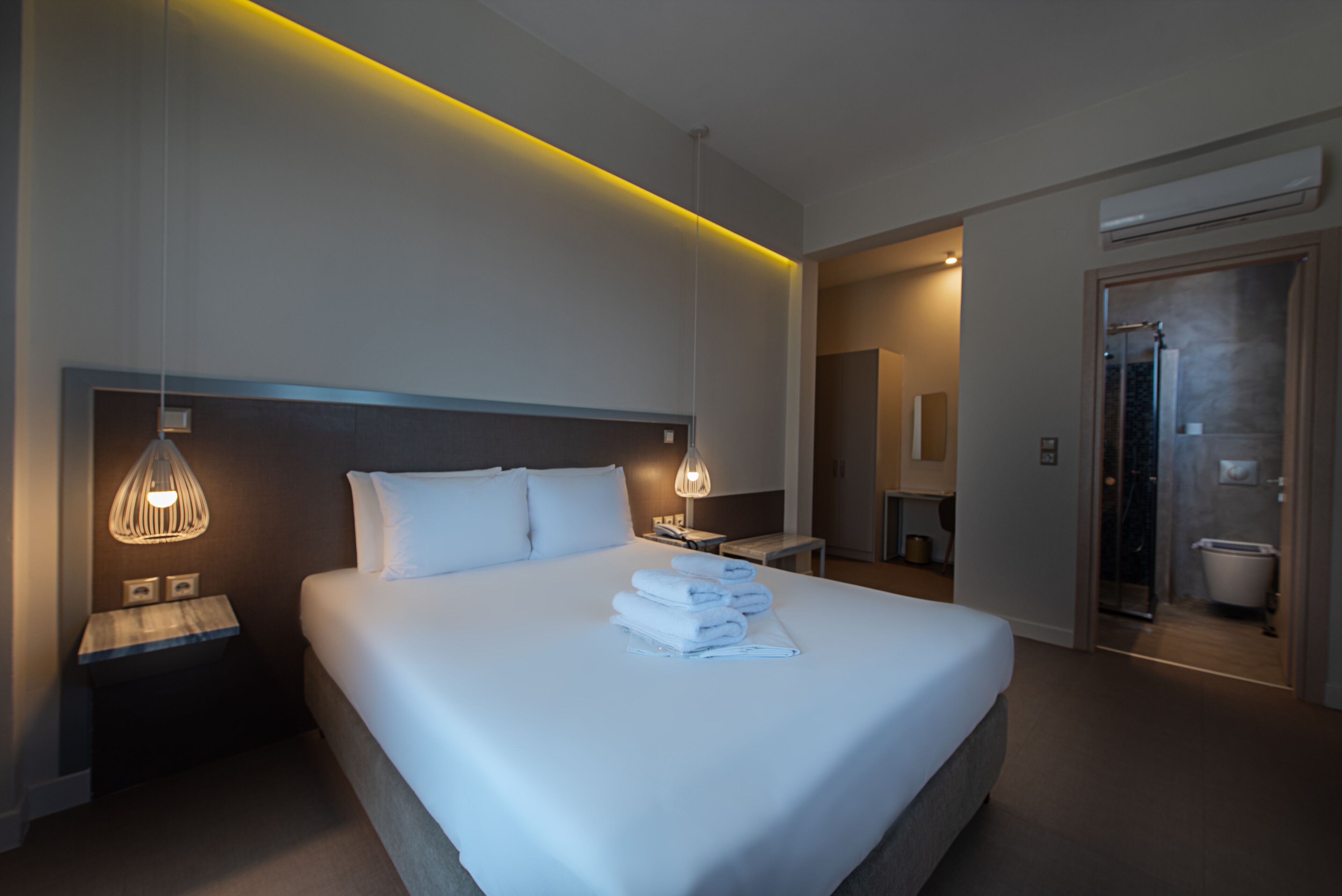 A modern hotel room with a large bed, bedside lamps, and a visible bathroom.