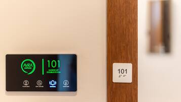 Pantalla digital que indica la habitación 101, señalada como habitación doble accesible, con instrucciones para esperar, no molestar y limpiar después de uno mismo.