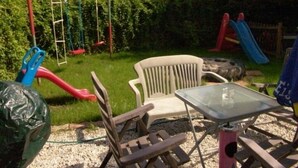 Un espace extérieur aménagé avec une table, des chaises et une balançoire.