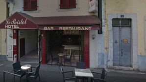 Ett hotell med en bar och en restaurang på bottenvåningen, med röda fönsterluckor och en skylt.