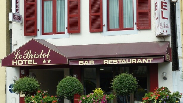 En byggnad med en skylt som visar att det är Le Bristol Hotel och en barrestaurang.