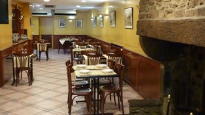 En restaurang med avskilda bås och bord, en vägg av sten och inramade tavlor på väggarna.
