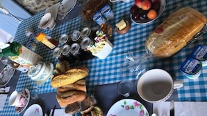 Une table mise pour le petit-déjeuner, avec du pain, des fruits, des produits laitiers et des condiments.