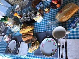 A table set for breakfast with bread, fruits, dairy products, and condiments.