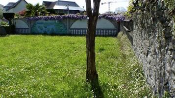 A grassy area with a tree and a stone wall.
