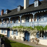 A traditional building with a balcony, a bicycle, and outdoor seating.