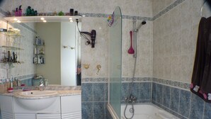 Une salle de bain avec un meuble-lavabo blanc, une douche en verre et une baignoire.