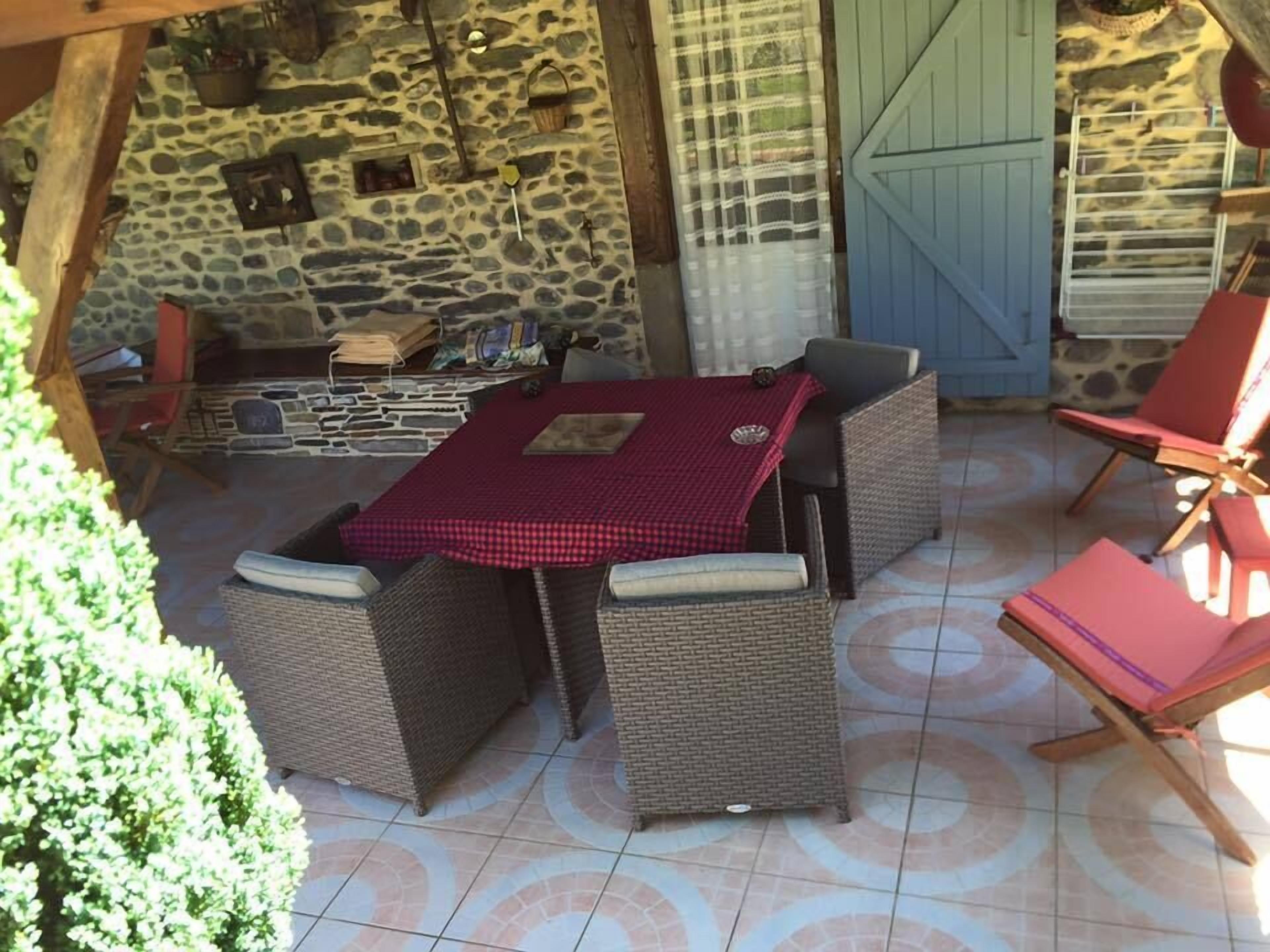 An outdoor patio with stone walls, wicker furniture, and a tiled floor.
