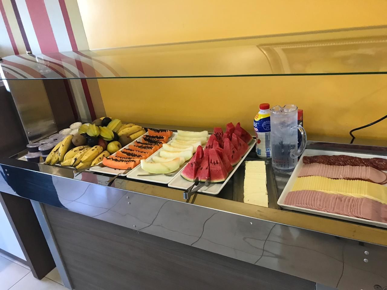 A buffet counter with various fruits and sliced meats.