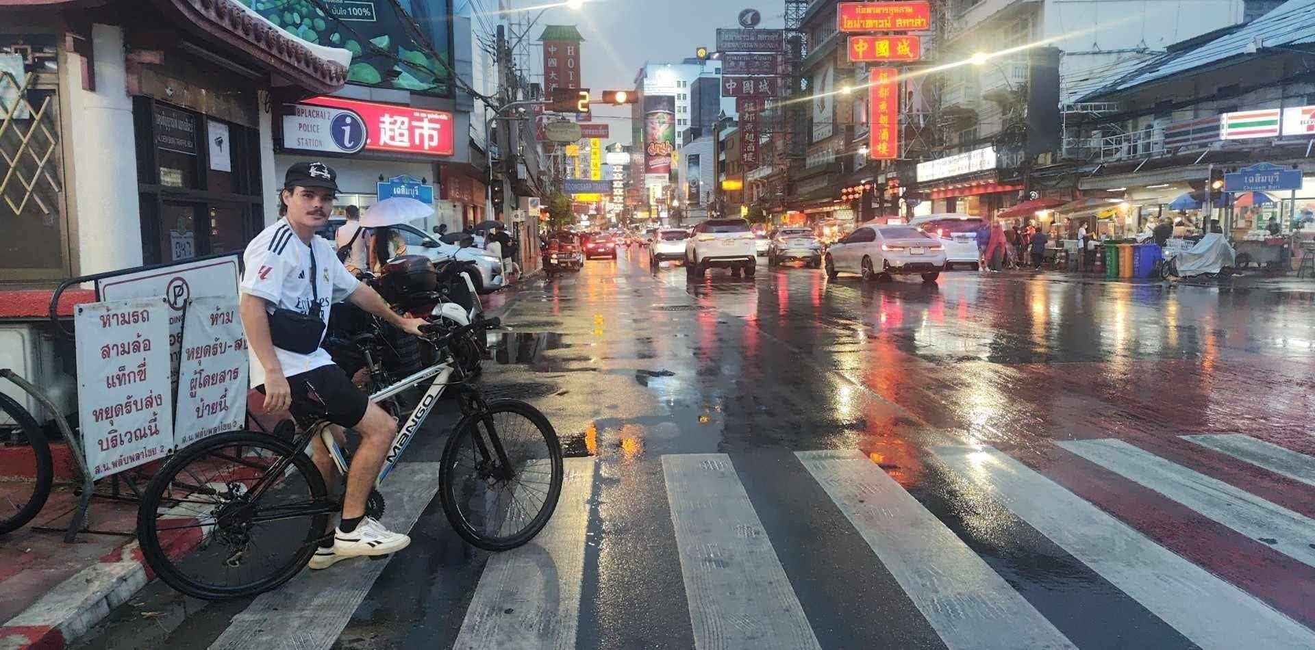 A busy urban street scene with a person on a bicycle crossing a zebra crossing.