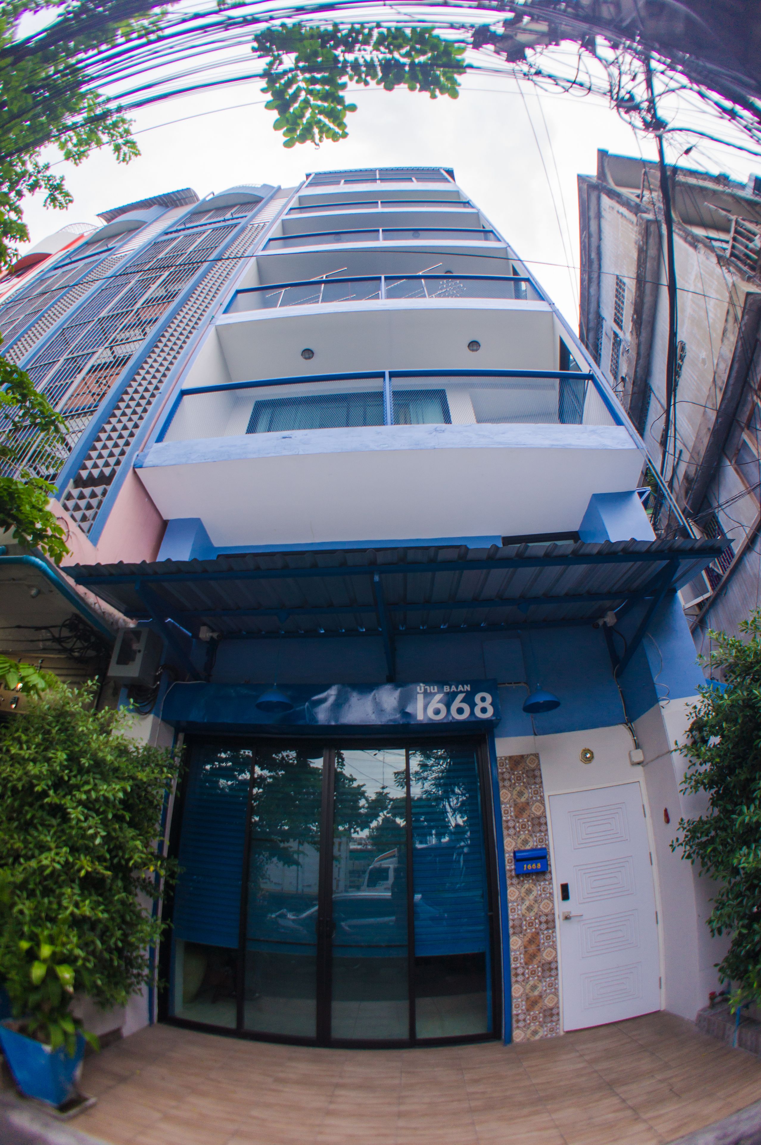 A multi-story building with a blue and white facade, a visible entrance with glass doors, and a number '1668' displayed above the entrance.