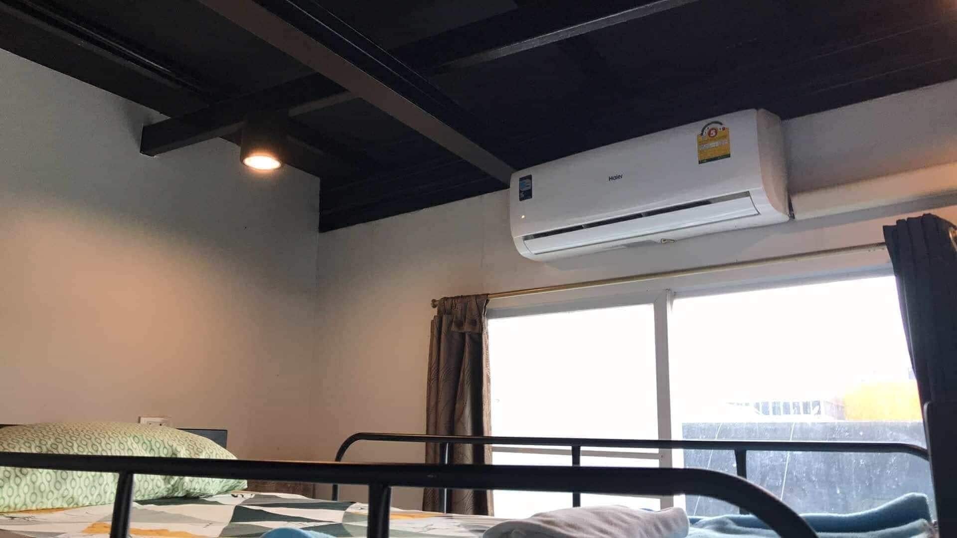 A room with a bed, a window with curtains, and an air conditioning unit.