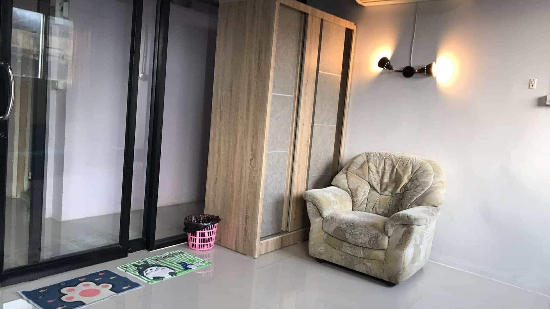 Ein modernes Zimmer mit bequemem Ohrensessel, Glastür und Wandpaneelen aus Holz.