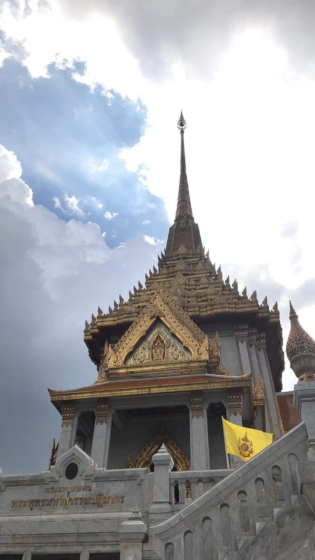 A temple with a pointed spire, ornate golden decorations, and a flag.