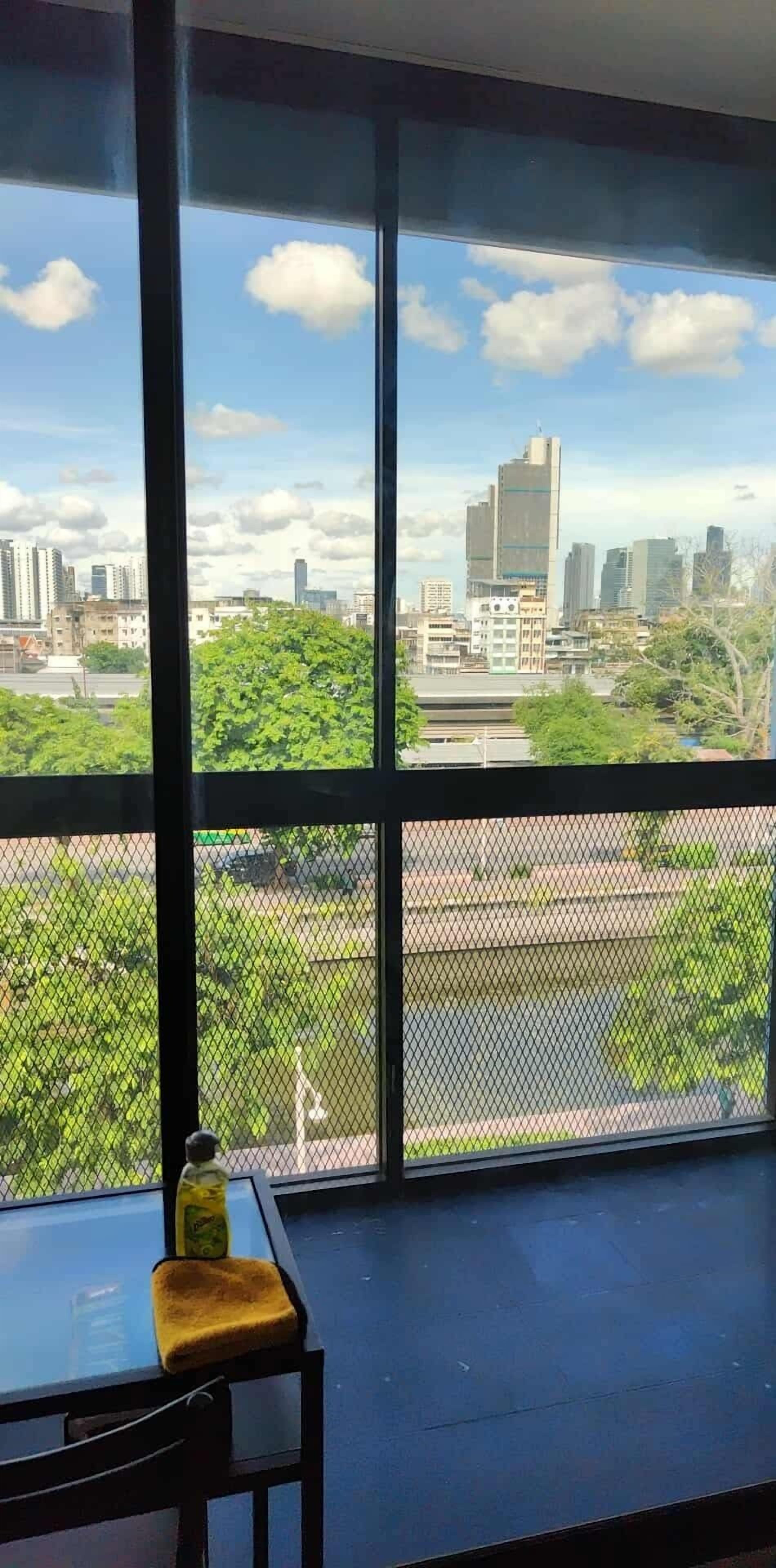 A room with large windows offering a view of a cityscape and greenery.