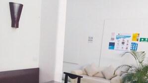 Uma área de recepção com um sofá, uma mesa pequena e um vaso de planta.