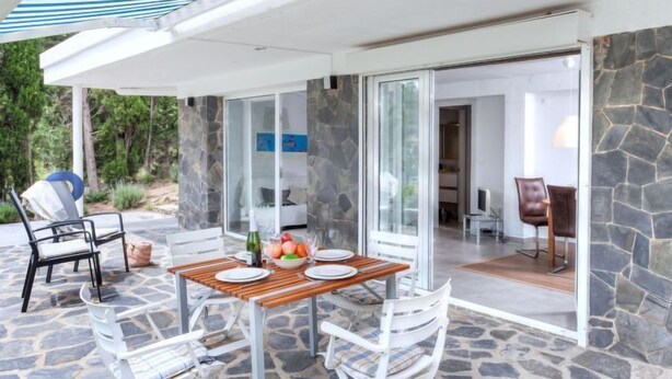 Eine Terrasse mit Esstisch, Steinböden und einer Glastür zu einem Innenbereich.