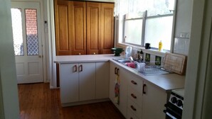 Une cuisine avec des meubles de rangement en bois, un plan de travail blanc, un évier et une fenêtre.