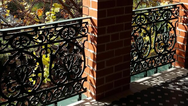Un balcon doté d’un sol à motifs, de piliers en briques et d’une rambarde en métal.