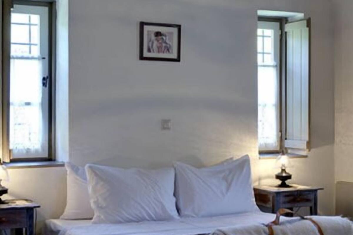A bedroom with a bed, two bedside tables, a window, and a picture on the wall.