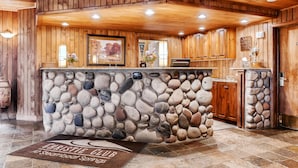 A reception area with a stone wall, wooden paneling, and a welcome mat.