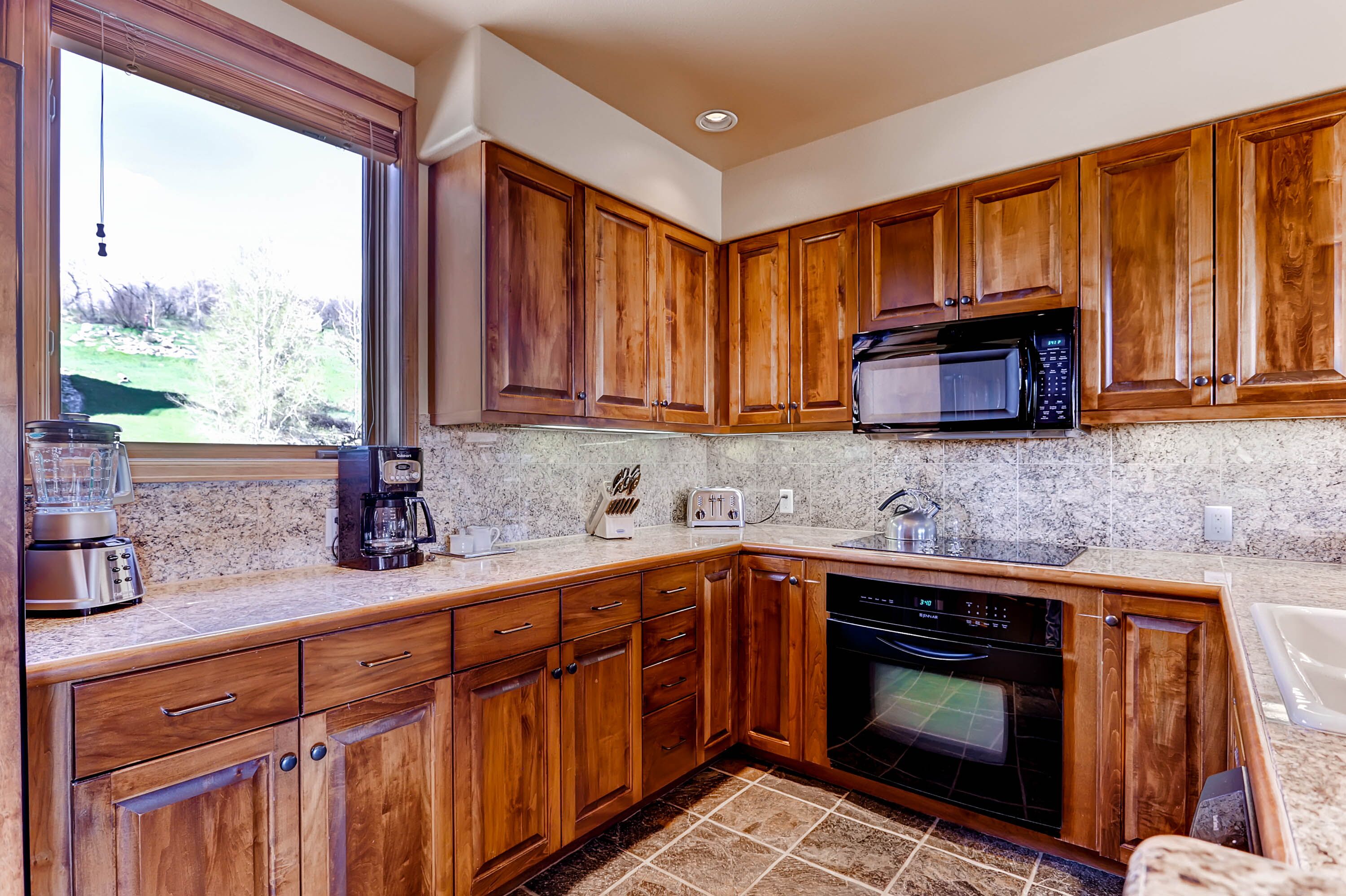 A kitchen with wooden cabinets, a microwave, a toaster, and a dishwasher.