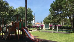 A playground with a slide, surrounded by trees and a grassy area.