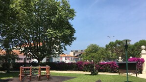 A park with a playground, a bench, and a trash bin.