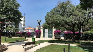 A park with a paved walkway, benches, and a green fence.