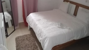 A bedroom with a bed, a mirror, and a door.