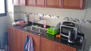 A kitchen with wooden cabinets, a sink, a microwave, and a dish rack.