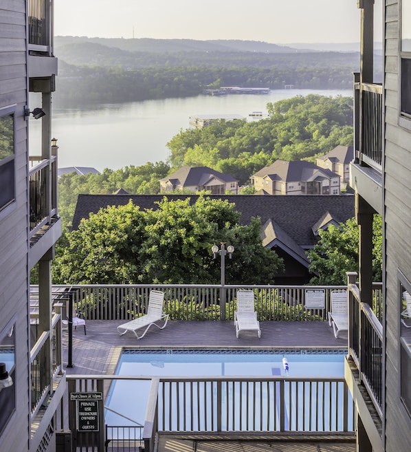 Relax by the serene rooftop pool overlooking a tranquil lake and lush greenery.