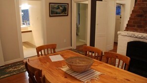 A dining area with a wooden table, four chairs, a woven basket, and a fireplace. - New Plymouth Central and Charming (New Plymouth)