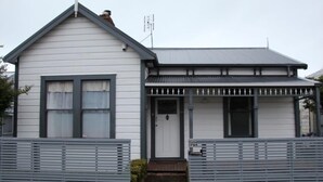 A single-story house with a gabled roof, a front porch with a railing, and a mailbox. - New Plymouth Central and Charming (New Plymouth)