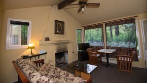 A living room with a fireplace, a ceiling fan, a sofa, a table, and a TV. - River View Garden Resort (Monte Rio)