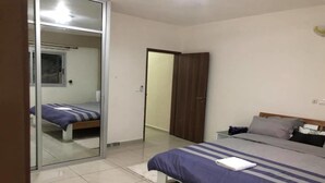 A bedroom with a bed, a wardrobe, and a mirror. - Résidence italien2  T3 (Abidjan)