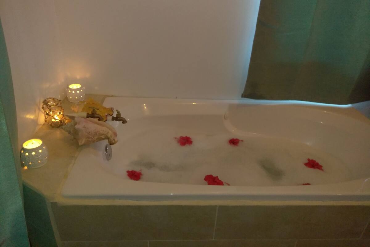 Una bañera con pétalos de rosa y velas.