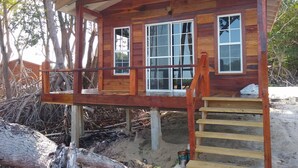 Una cabaña de madera con un porche, ventanas amplias y una escalera.
