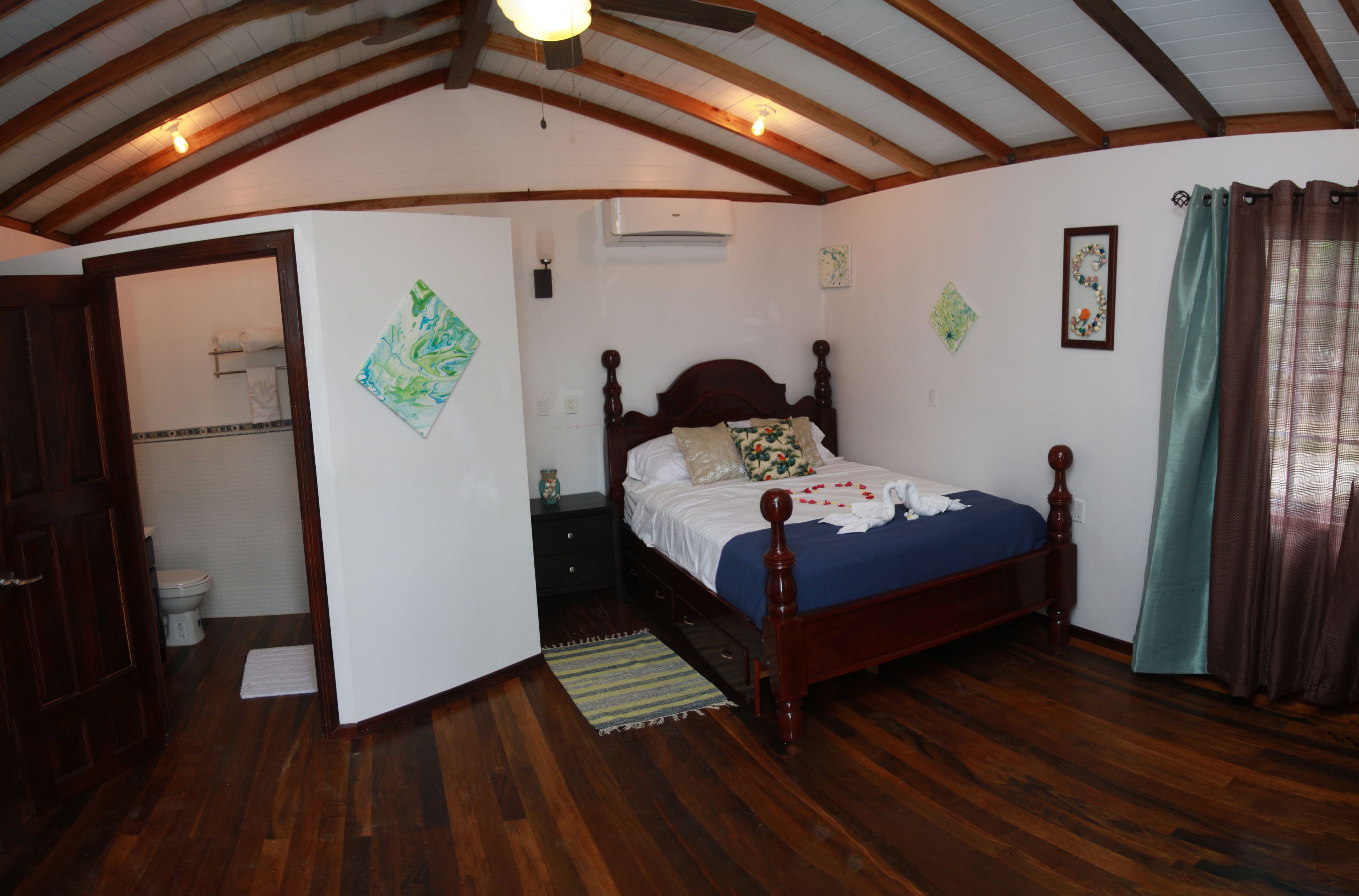 A bedroom with a wooden bed, a wooden ceiling, and a white wall with an air conditioner.
