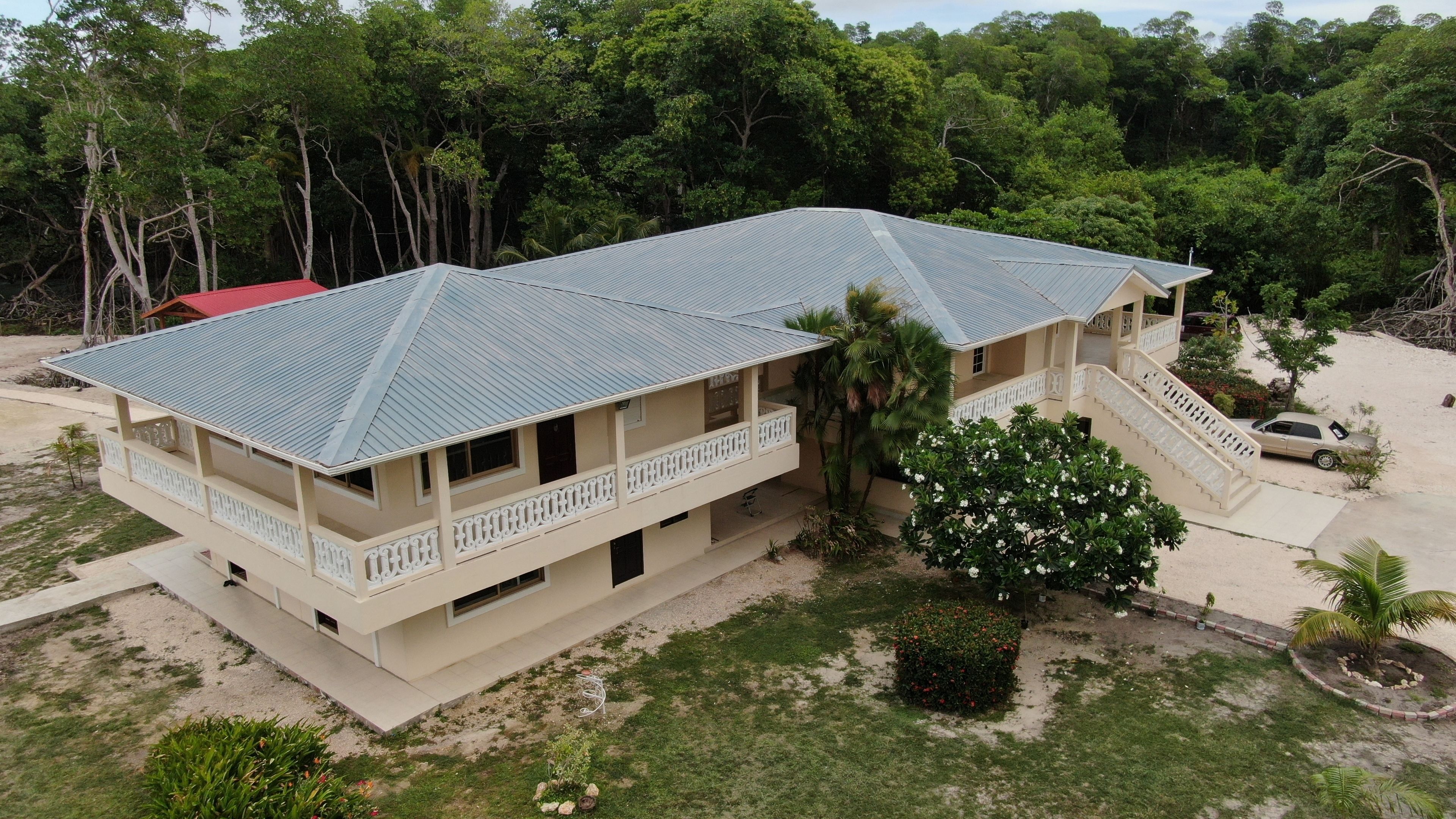 A two-story building with a flat roof, a balcony on the second floor, and a staircase leading to the upper level.