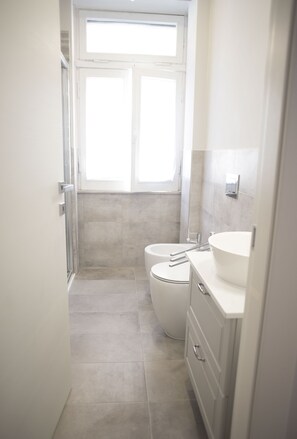 Un baño pequeño con inodoro, lavamanos y ducha.