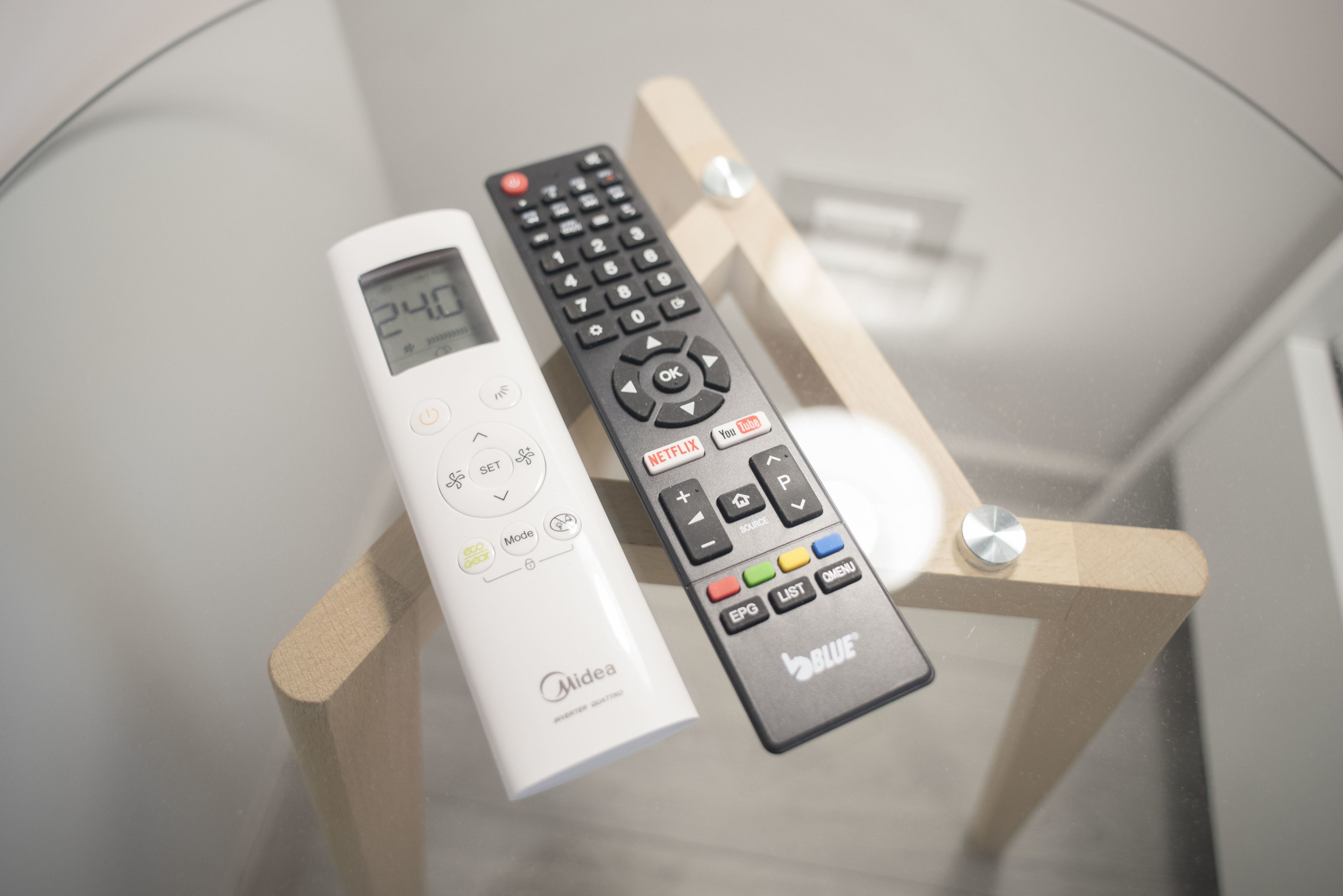 Deux télécommandes, une blanche et une noire, posées sur un support en bois.