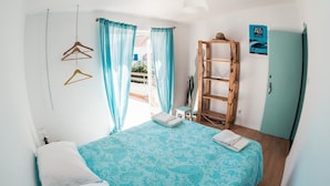 Un dormitorio con cama, una escalera de madera, armario y ventana con cortinas.