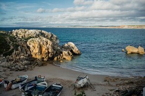 A rocky coastline with boats on the shore and a clear view of the sea. - Native Surfhouse - Hostel (Lourinha)